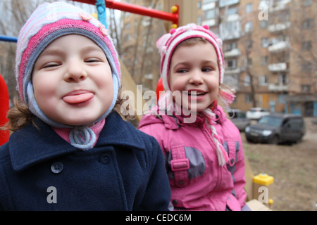 On playground the girl puts out tongue,  second laughs Stock Photo