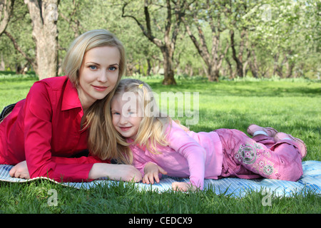 Mother with daughter lie on grass in park in spring Stock Photo