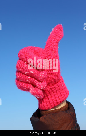 Hand in red glove against  blue sky shows gesture ok Stock Photo