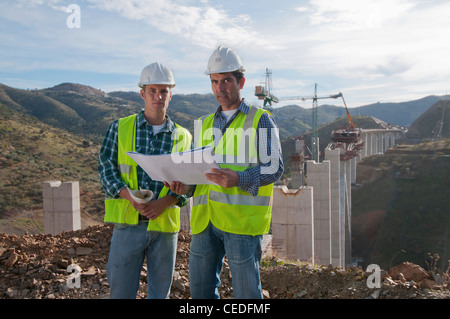 Construction workers looking at blueprint at construction site Stock Photo