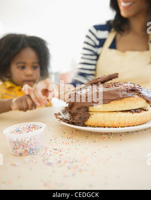African American mother and son icing cake Stock Photo