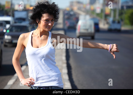 young woman hitchhiking on highway Stock Photo