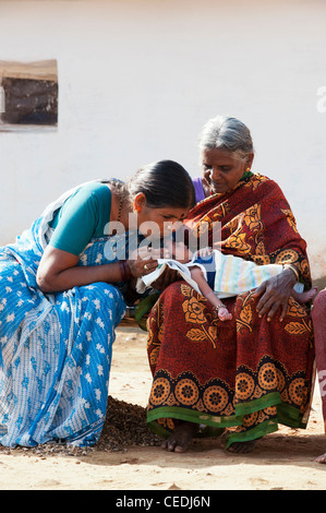 Indian grandmothers holding  and kissing a new born baby in a rural indian village. Andhra Pradesh, India Stock Photo