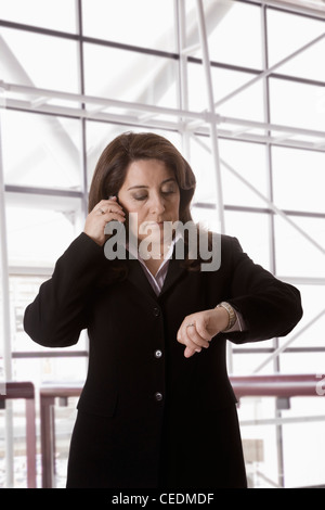 Hispanic businesswoman talking on cell phone checking the time