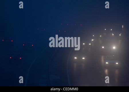 Cars in the fog on road in England at night Stock Photo
