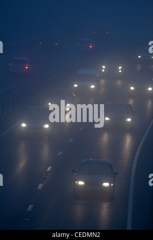 Cars in the fog on road in England at night Stock Photo