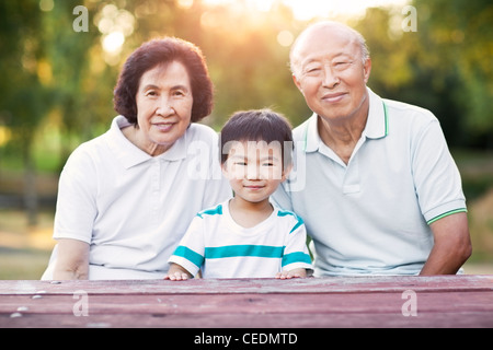 Chinese grandparents sitting outdoors with grandson Stock Photo