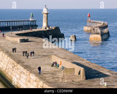 People enjoying a walk on Whitby East Pier on a sunny winters day Stock Photo