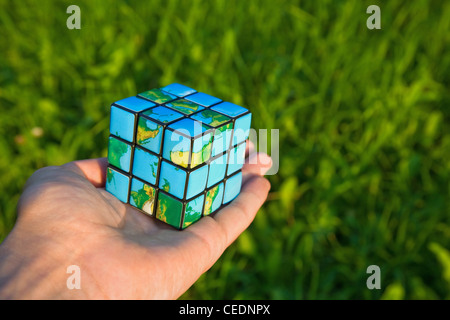 Cube in the manner of planets land on palm on background of the herb Stock Photo