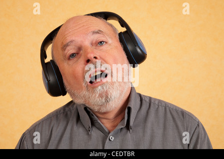 Elderly man with headphones, sings Stock Photo
