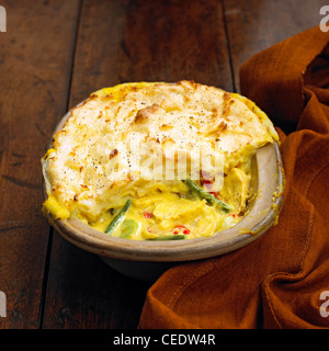 Vegetable and chicken pie topped with potato in an oven dish on wooden surface, close-up Stock Photo