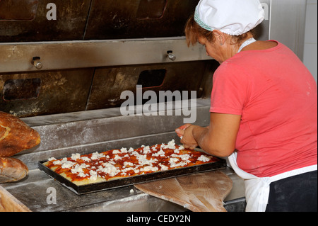 Italy, Basilicata, Roccanova, bakery, bread oven, baker preparing typical italian pizza with tomato and mozzarella Stock Photo