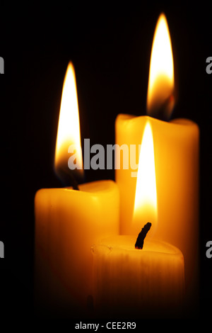 Three burning candles over a black background Stock Photo - Alamy