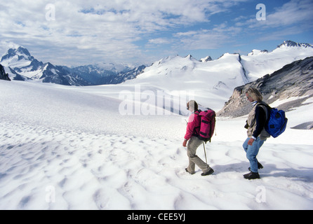 Two female hikers make a summertime exploration of the snow-covered Bugaboo range in the ancient Purcell Mountains of British Columbia, Canada. Stock Photo