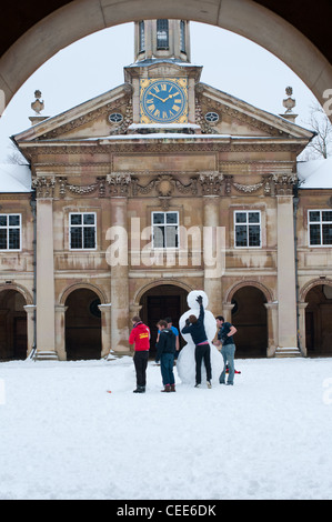 Students making a snowman at Emmanuel College, St. Andrews Street, Cambridge, UK Stock Photo