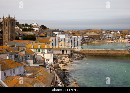 Church and rooftops at St Ives, cornwall,uk. Lichen covered rooftops, st ives harbour beach and granite stone jetty. Stock Photo