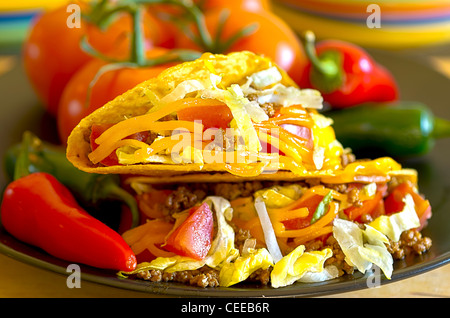 Closeup of tacos on plate with vine ripe tomatoes, red and green chili peppers. Stock Photo