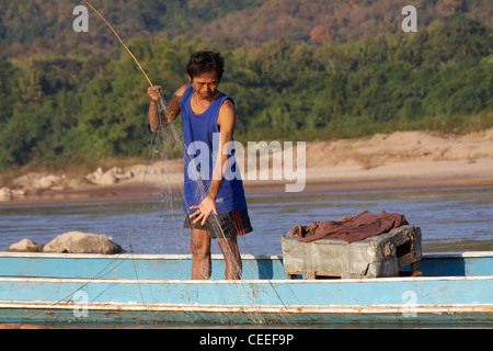 Man fishing with nets from a boat on the Mekong river in the evening light near Luang Prabang in Laos Stock Photo