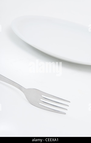 Beautiful fork and a white plate, a kitchen accessories close up Stock Photo