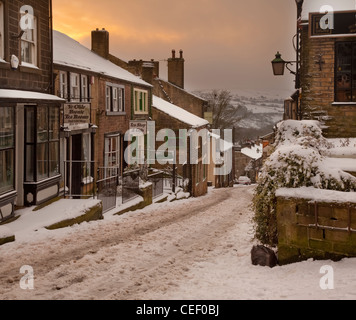 Looking down The snow covered main Street of Haworth, West Yorkshire in Winter at sunrise. Stock Photo