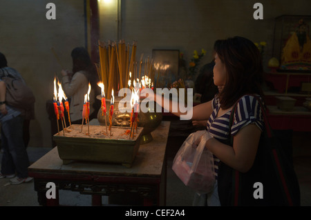 dh Man Mo Temple SHEUNG WAN HONG KONG Chinese Woman lighting joss stick incense urns taoist temple china person burning candle