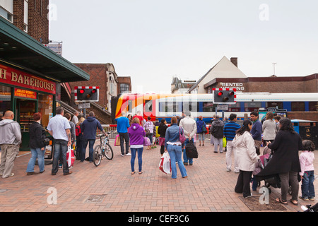 People waiting for train to pass at level crossing in the town centre of Poole, Dorset, England. Stock Photo