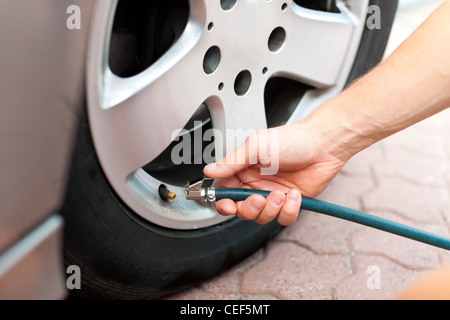 Man - only hand to be seen - is controlling the tire pressure of his car Stock Photo