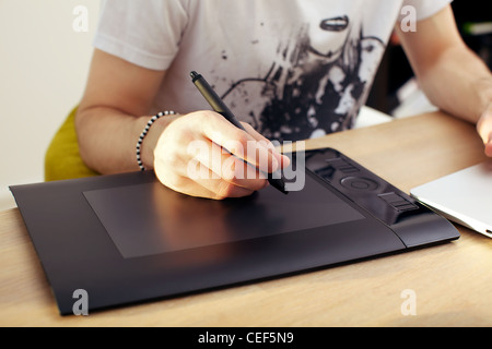Closeup of a mans hand holding a pen stylus over a touchpad graphics tablet. Stock Photo