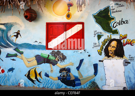 Mural on wall of diving tour operators office with Coiba Island, diver down flag on wooden shutters, Bob Marley and a surfer, Santa Catalina, Panama Stock Photo