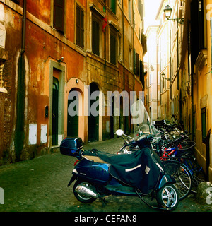 old street in the historic center of Rome with motor scooters and bicycles Stock Photo