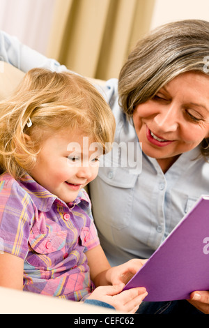 Grandmother and little girl reading book happy together at home Stock Photo