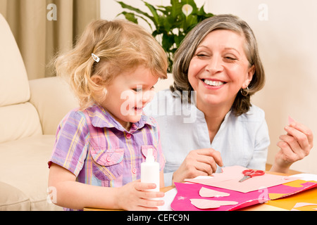 Grandmother with granddaughter playing together glue hearts on paper Stock Photo