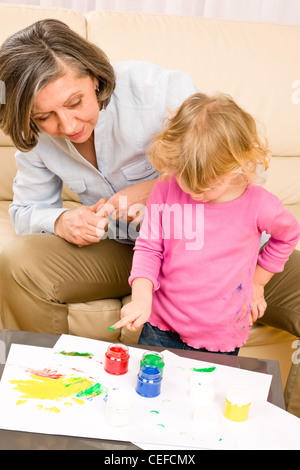Grandmother with granddaughter playing together paint handprints on paper Stock Photo