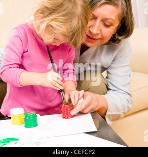 Grandmother with granddaughter playing together paint handprints on paper Stock Photo