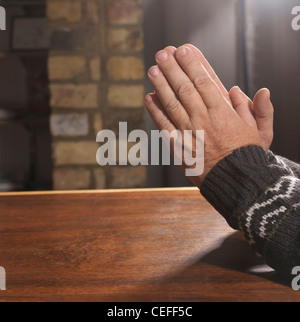 Older man with hands clasped in prayer Stock Photo