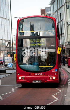 Red double decker bus driving along a bus lane on a street in the city of London, England. Stock Photo