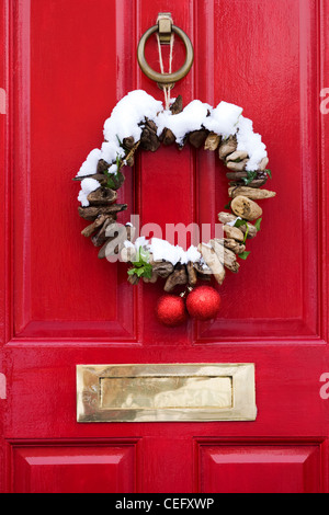 Decorative driftwood Christmas wreath hanging on a red front door. Stock Photo