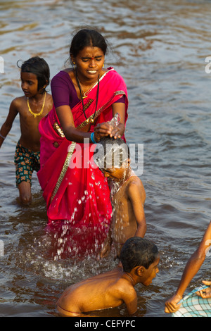 Indian mother bathing his son on the waters of Tungabhadra river, Hampi ...