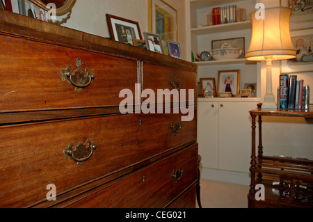 Victorian mahogany chest of drawers and lighted lamp in corner of traditional bedroom Stock Photo