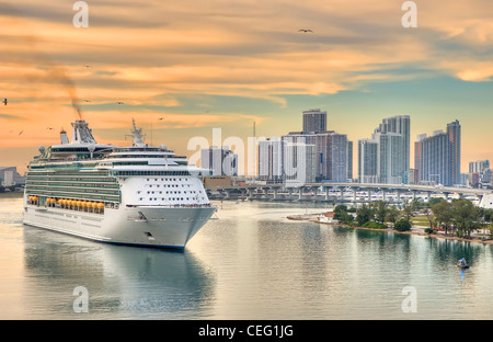 Cruise ship leaving the port of Miami, Florida on a cruise during sunset. Downtown Miami is in the background. Stock Photo