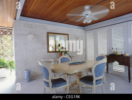 Ceiling Fan Above Cream Table And Traditional Blue Upholstered Chairs In Modern Caribbean Dining Room With Ceiling Fan Above Cream Table And Traditional Blue Upholstered Chairs In Modern Caribbean Dining Room With