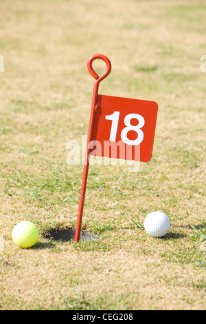 18th hole on a golf putting green with two golf balls. Stock Photo
