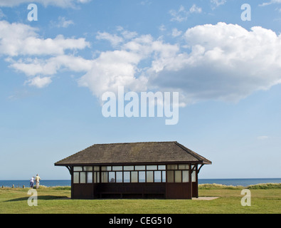 Two people enjoying the view  from near Cliff top shelter Barton on Sea  Hampshire under a cloudy sky Stock Photo