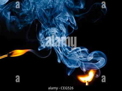 Striking of a match showing smoke rising against a black background. Stock Photo
