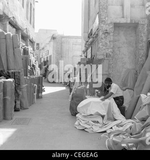 A man works at stitching heavy cloth signs on an old sewing machine in the back streets of Souq Waqif, in Doha, Qatar, Stock Photo