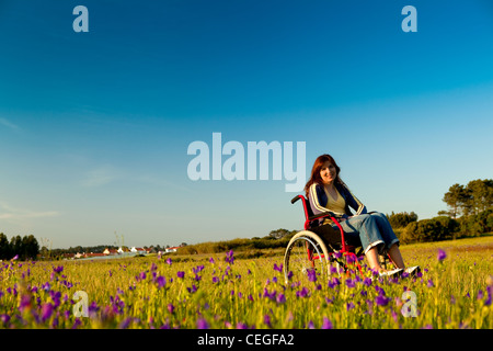 Handicapped woman on a wheelchair over a green meadow Stock Photo