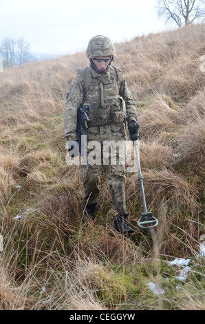 A British army solder 'Vallon man' looking for IED's using a Vallon metal detector, he will lead a patrol, sweeping the route fo Stock Photo