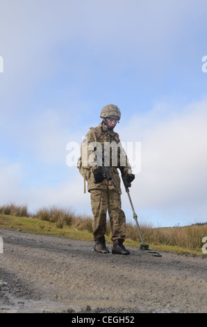 A British army solder 'Vallon man' looking for IED's using a Vallon metal detector, he will lead a patrol, sweeping the route fo Stock Photo