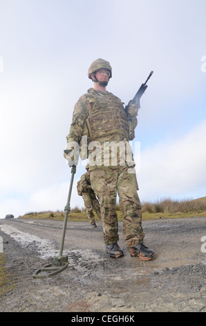 A British army solder 'Vallon man' looking for IED's using a Vallon metal detector, he will lead a patrol, sweeping the route fo Stock Photo