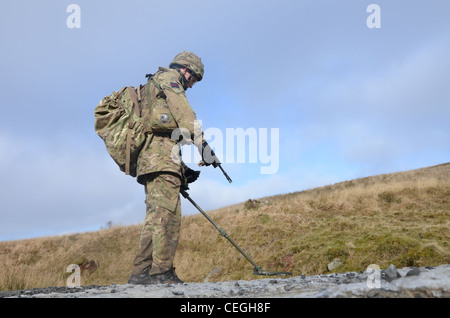 A British army solder 'Vallon man' looking for IED's using a Vallon metal detector, he will lead a patrol, sweeping the route fo Stock Photo